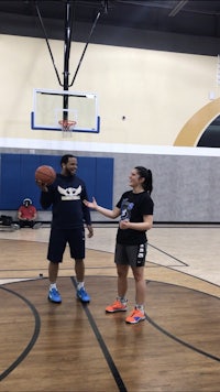 two people standing on a basketball court talking to each other